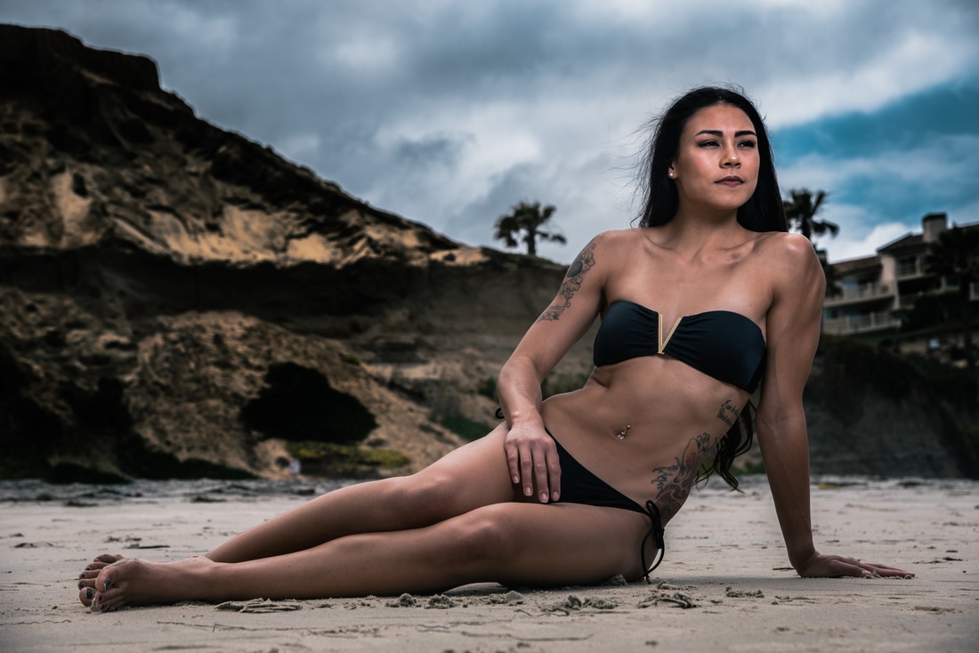fitness model laying on the beach in a black bikini